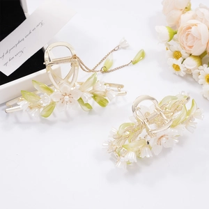 Detail of floral hair claws with white camellias, green leaves and hanging metal tassels
