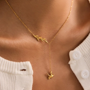 Elegant 18K gold plated stainless steel Y-necklace with bird and leaf charms on a model