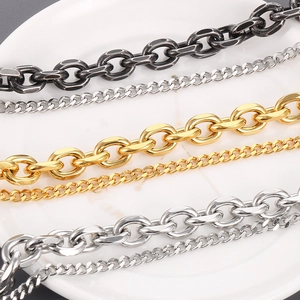 Macro detail of mixed gold, silver, and vintage black steel curb chains on white plate