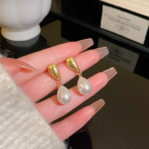 Detailed close-up of French Baroque teardrop pearl earrings with gold metallic finish