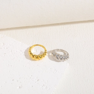 Detail of twisted croissant rings in gold and silver finish on white stone