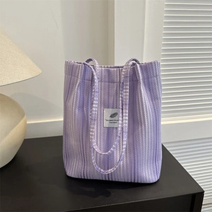 Dettaglio della borsa tote in tela a righe viola e bianche su un tavolo in legno scuro