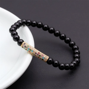 Macro detail of black beaded bracelet featuring a colorful zircon-encrusted gold tube