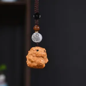 Makroaufnahme eines handgeschnitzten Thuja-Holz-Fabeltier-Anhängers mit Segensperle