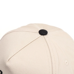 Detailed macro view of beige twill cotton baseball cap top with black button and stitching