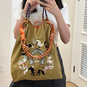 Detail of khaki nylon tote bag featuring equestrian horse embroidery and braided rope handle