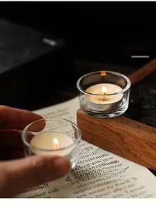 Primo piano di un portacandele in vetro minimalista con un lumino bianco acceso