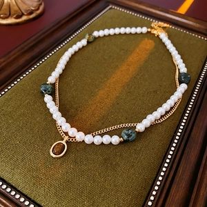 Détail d'un collier doré à deux rangs avec perles et pendentif œil de tigre