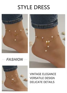 Detail of gold layered anklets with pearls and charms on beach background