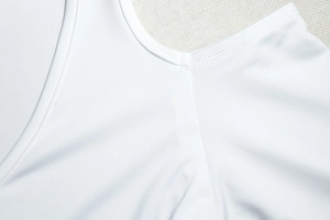 Detail of white knit dress showing round neckline and double-needle stitching quality