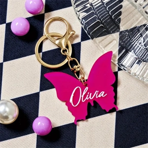 Macro view of a fuchsia resin butterfly keychain with personalized Olivia name text