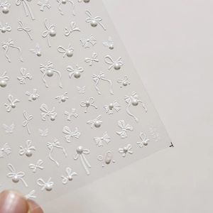 Macro shot of embossed white 3D nail art stickers with bowknot and pearl designs