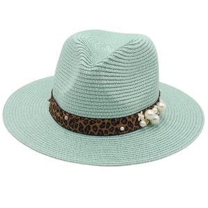 Detail of mint green straw hat featuring leopard print band with faux pearls and flowers