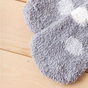 Detailed close-up of grey coral fleece socks with white polka dots on wood background