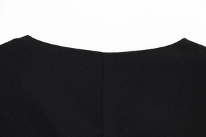 Macro detail of black asymmetrical vest neckline showing textured crepe fabric stitching