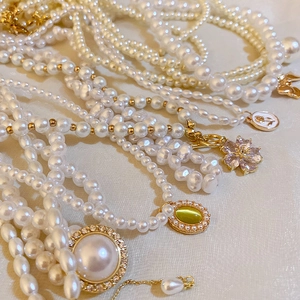 Colliers et bracelets en perles vintage avec pendentifs dorés sur tissu en soie beige