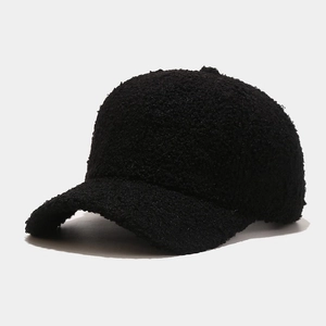 Detailed view of the thick black faux lamb wool fabric texture on a baseball cap