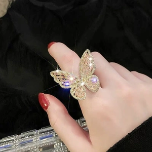 Detailed view of luxury gold butterfly ring with pink zircon crystals on finger