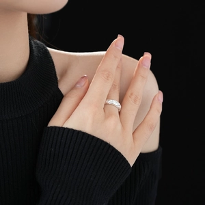 Detailed close-up of a silver textured twist ring with zircons worn on a model finger