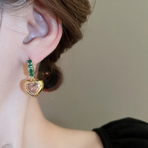 Macro view of vintage heart earrings with green zircons and pink stone pendant
