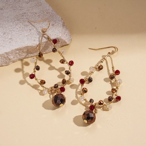 Détail de boucles d'oreilles ethniques en fil d'or avec perles de verre rouges et brunes