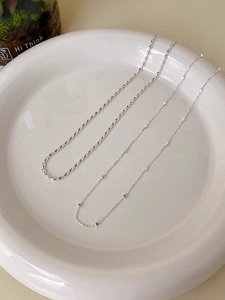 Dettaglio di collane in argento s925 con perline quadrate su vassoio di ceramica bianca