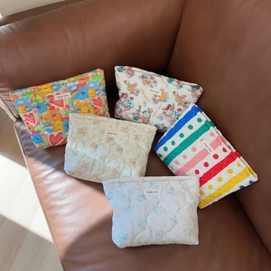 Quilted floral and bear pattern cotton cosmetic bags displayed on a leather surface