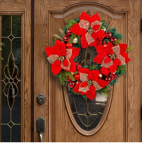 Close-up of a festive red poinsettia Christmas wreath hanging on a dark wooden door