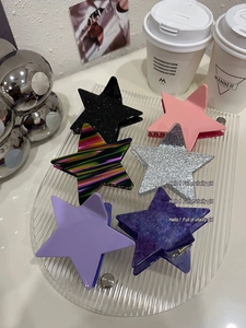 Detail of star-shaped hair clips in various colors and patterns on a glass tray
