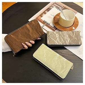Three long zip wallets in velvet texture shown with a coffee cup on a wooden table