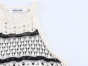 Detailed view of white knit tank top featuring hollow-out lace and geometric patterned trim
