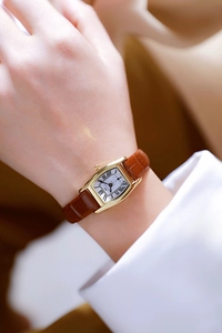 Detail of a brown leather strap ladies watch with a gold tonneau case and Roman numerals