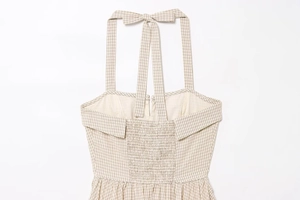 Detail of beige plaid halter dress featuring neck tie and smocked elastic back