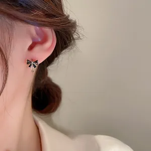 Detailed view of elegant black bow earrings with silver metallic accents on model