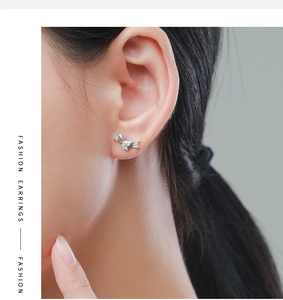 Close-up of minimalist S925 sterling silver puppy stud earring worn on model's ear