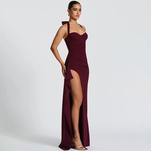 Detail of the high-slit hem and flowing burgundy fabric on the backless halter dress