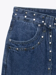 Détail de rivets argentés et coutures sur la taille du jean en denim bleu foncé