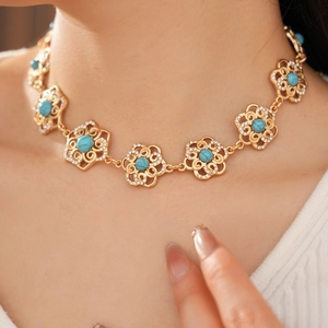Close-up of vintage gold flower necklace with turquoise stone and sparkling rhinestones