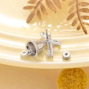 Elegant Christmas bell bow earrings in silver steel on a warm ceramic tray display