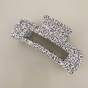 Detail view of large rectangular hair claw clip with black and white speckled pattern
