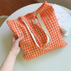 Detail view of cotton tote bag with orange grid pattern and internal woven label