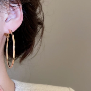 Close-up of a model wearing large golden round hoop earrings with a metallic finish