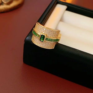 Macro shot of gold-plated ring featuring rectangular green emerald and pavé-set zircon