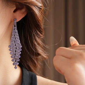 Vue détaillée des boucles d'oreilles à pompons en strass violets sur un mannequin