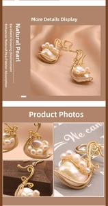 Detail of natural baroque pearls on golden swan earrings set on silk and wood