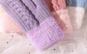 Detail of cable knit winter gloves with thick faux fur cuffs in pastel colors