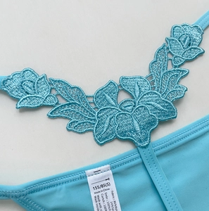 Detailed embroidery on light blue lace thong with size S care label and nylon fabric