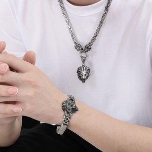Close-up of vintage lion head necklace and open bracelet set in silver-tone stainless steel