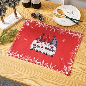 Close-up of red festive placemat with three Christmas gnomes and snowflake patterns