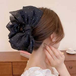 Détail d'une grande pince à cheveux avec nœud en mousseline noire à pois sur cheveux